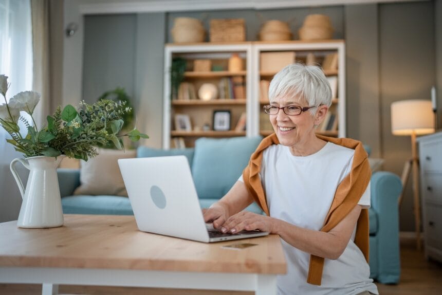 senioara foloseste laptopul si zambeste